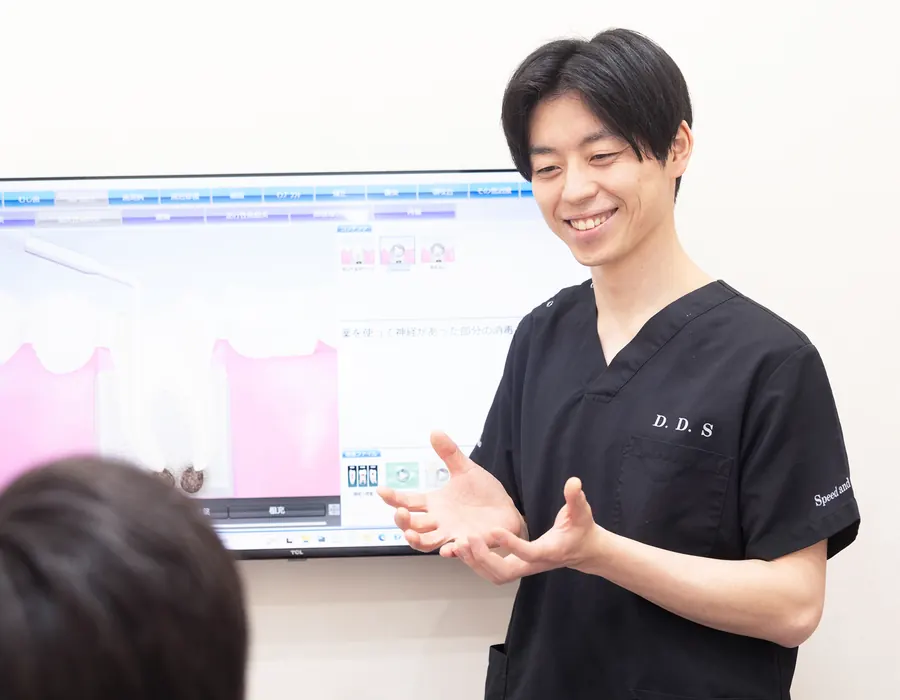 モニターの画像を使って治療内容を説明する歯科医師